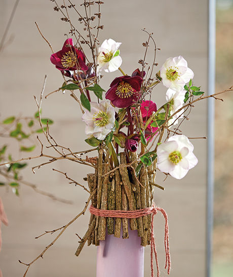 Diese rosa Vase wurde mit einem Zweigrand dekoriert und zeigt die Aarendelle Sorten Nora Purple und Bella Picotee.